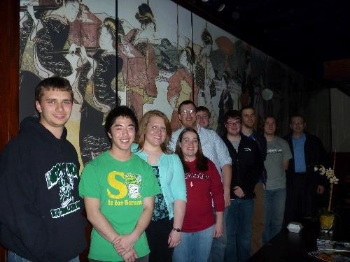 Photo of trombone students in front of restaurant mural at dinner at during Winter 2010.